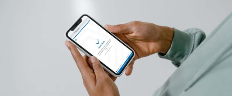Person holding a smartphone displaying a digital verification confirmation.