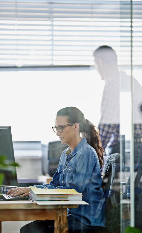 Woman working on a computer at an office desk.