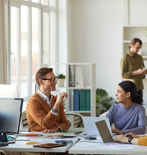 Two colleagues discussing ideas around a shared office desk.