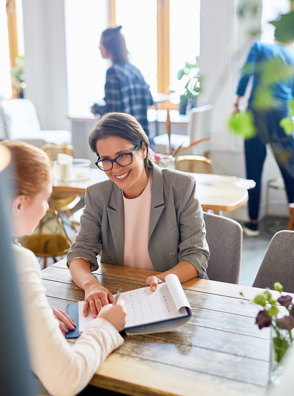HR professional reviewing documents with a colleague, illustrating digital employee onboarding and payroll processes.