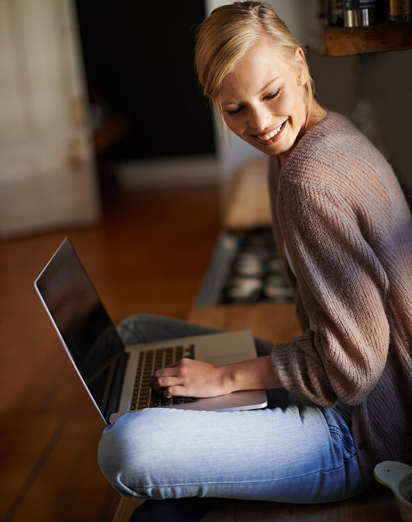 Woman using a laptop at home, illustrating access to the FINcredible WebApp.