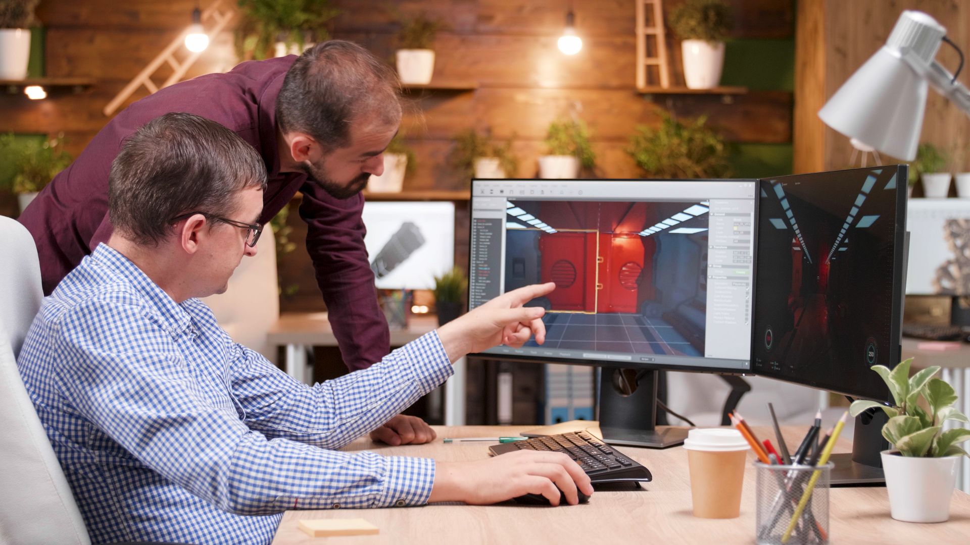 Two colleagues reviewing a 3D architectural design on a desktop computer.